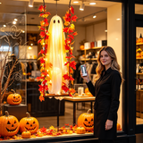 BooLuma swinging ghost displayed in a storefront window with pumpkins
